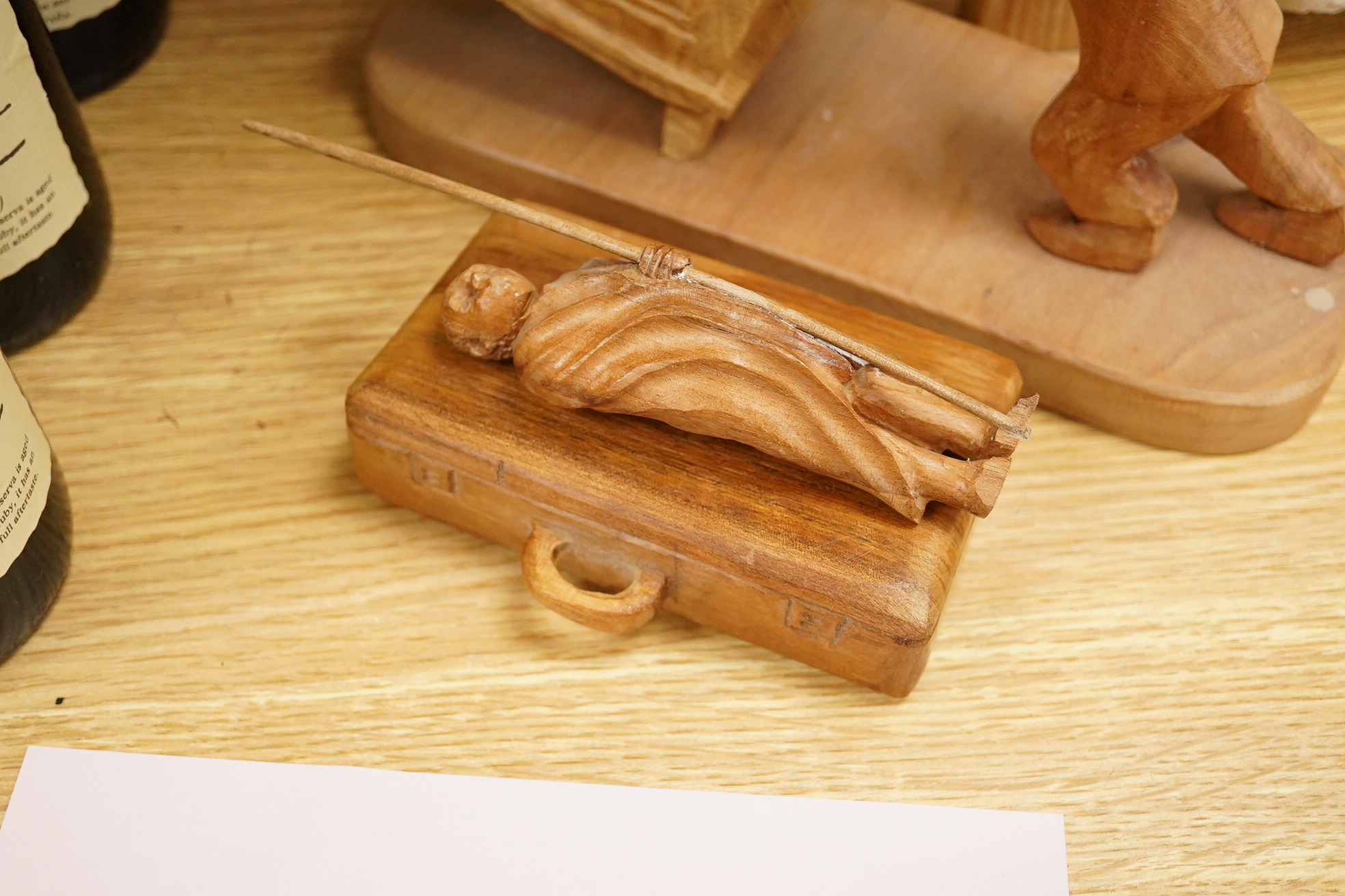 Pierre Decorse (b.1953), a naturalistically modelled wooden sculpture of a grandfather clock and a figure, together with two other sculptures comprising a suitcase and figure, largest 42cm high